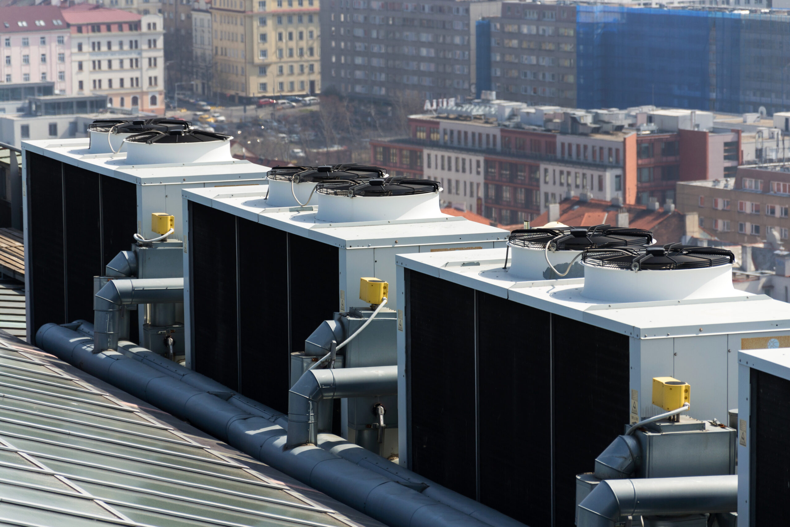 Air conditioning ventilators on roof with houses in background on a sunny day